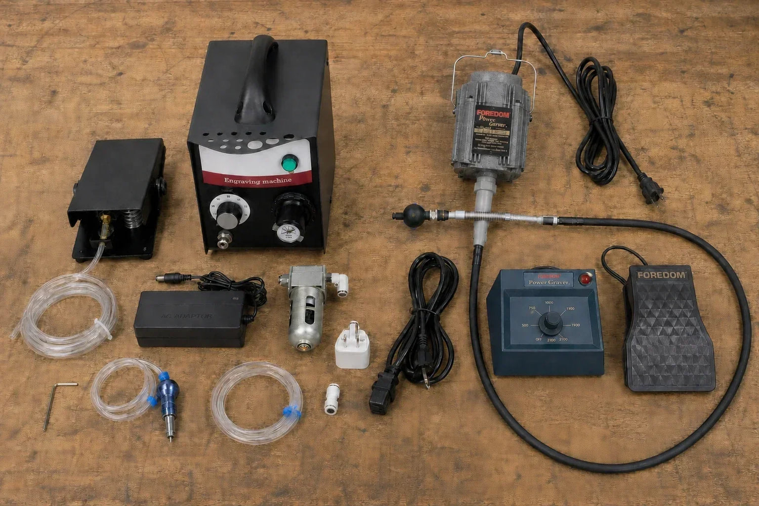 Side-by-side comparison of accessories included with the Foredom PowerGraver and Tooltos HH-G02 pneumatic engraving machine, laid out on a wooden surface.